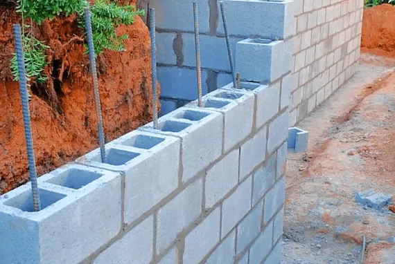 Concrete block foundation wall under construction with exposed rebar reinforcement