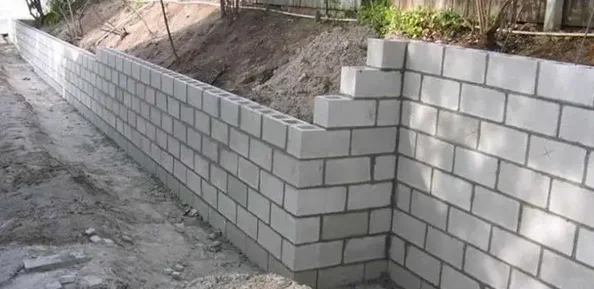 Newly built concrete block retaining wall along a graded backyard slope