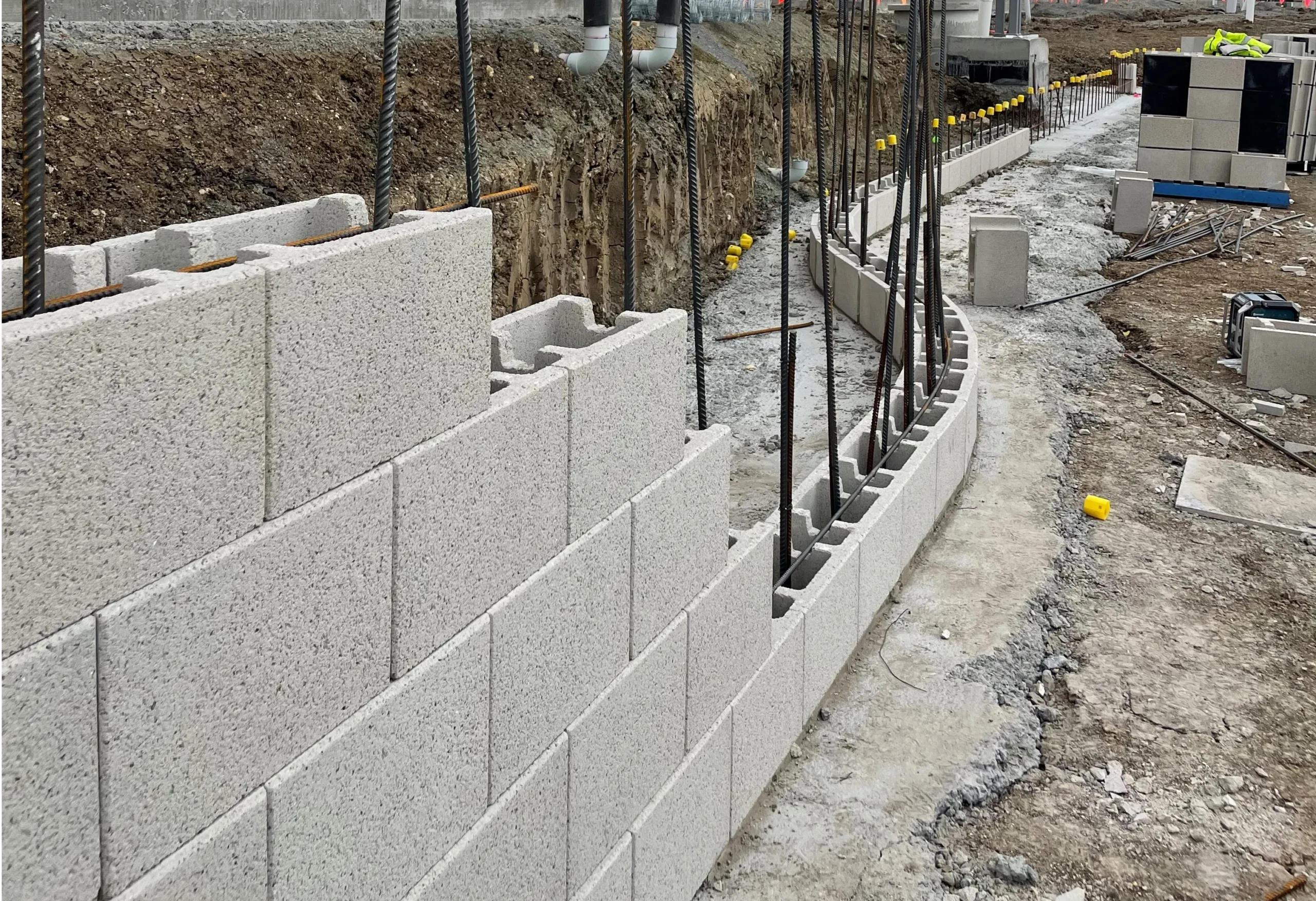 Curved concrete block foundation wall with rebar at large commercial construction site
