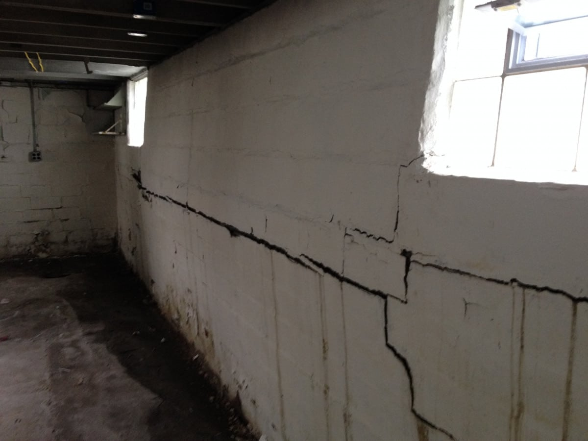 Horizontal crack running along painted basement wall near window from wall bowing