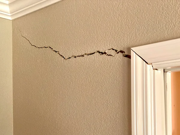 Horizontal crack running along wall near ceiling and door frame from foundation movement